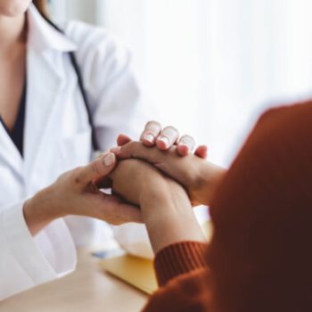 Asian doctor woman encourage young woman patient by holding hand